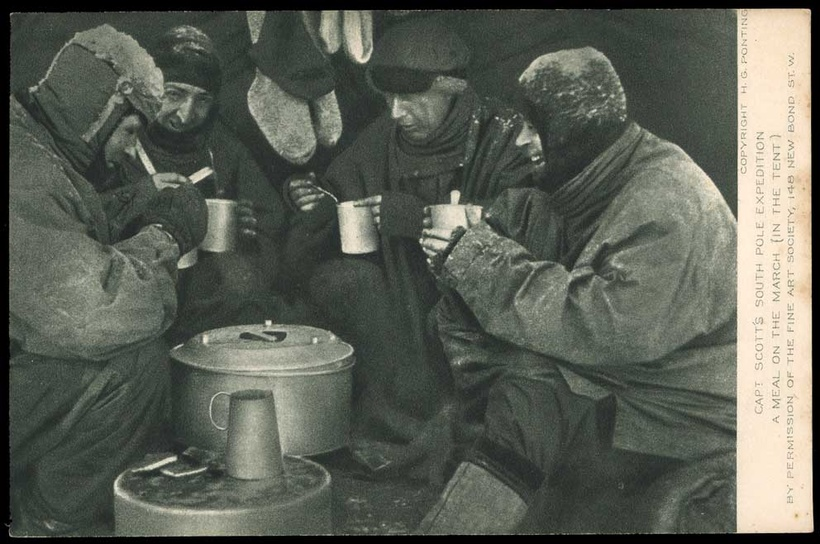 Four men in a cluttered tent, laughing. A frame from Ponting's film 90° South.