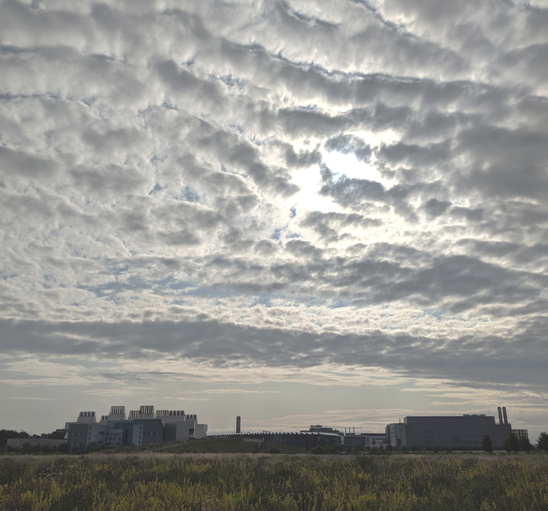 A vast fenland sky with a thin skiff of cloud, over the many blocky buildings of Addenbrooke's Biomedical Campus