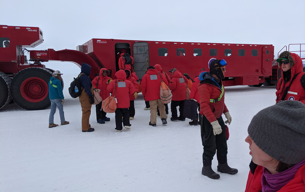 Arriving passengers board the passenger compartment of the Kress tractor at Phoenix Airfield, Antarctica.