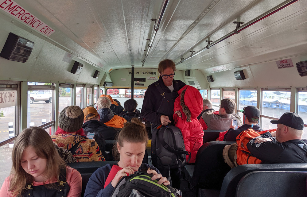 A man walks down the aisle of a school bus filled with people going to board an Antarctic-bound C-17 in Christchurch.